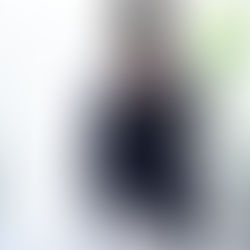 Person in glasses giving myofascial release therapy to someone lying face down. Bright room with white blinds and a green plant in the background.