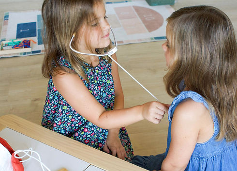 Two young girls in dresses playing doctor