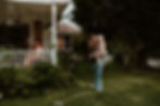a mother holds her toddler as a father reads to his son on the front porch swing