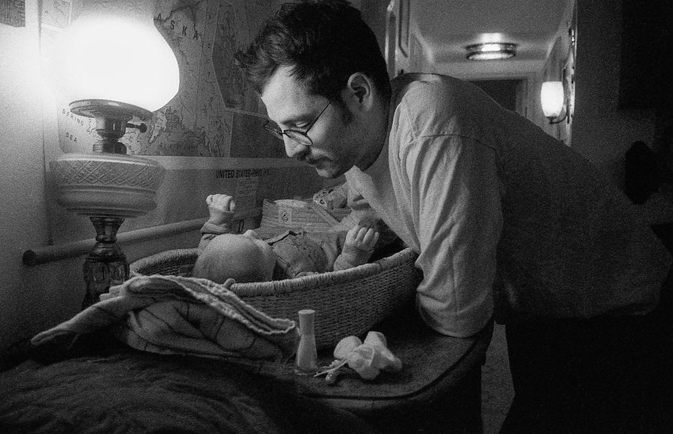 A black and whit film photograph of a father and newborn