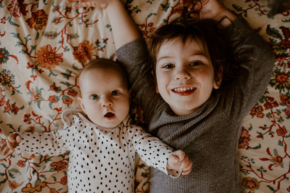 brother and sister on their mom's bed during an in-home family portrait session