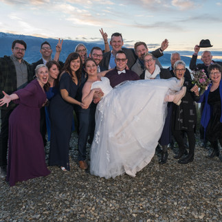 Group photo, old work mates holding up the bride with groom overlooking lake and mountains NZ
