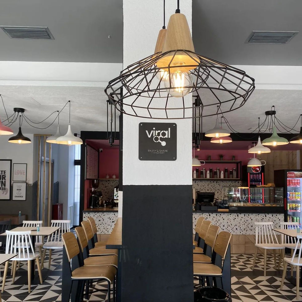 Large black wireframe pendant lamp with exposed bulb, positioned centrally in the café interior.