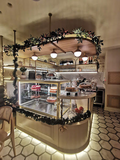 Close-up of central bar counter with display case lit from below, pendant globe fixtures above, and garland decoration with integrated fairy lights.