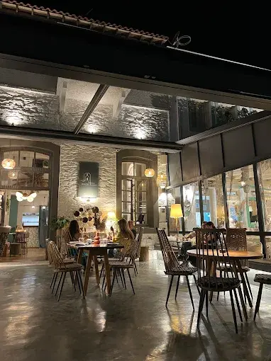 Exterior café view at night with warm wall sconces and pendant lights softly glowing above outdoor diners.