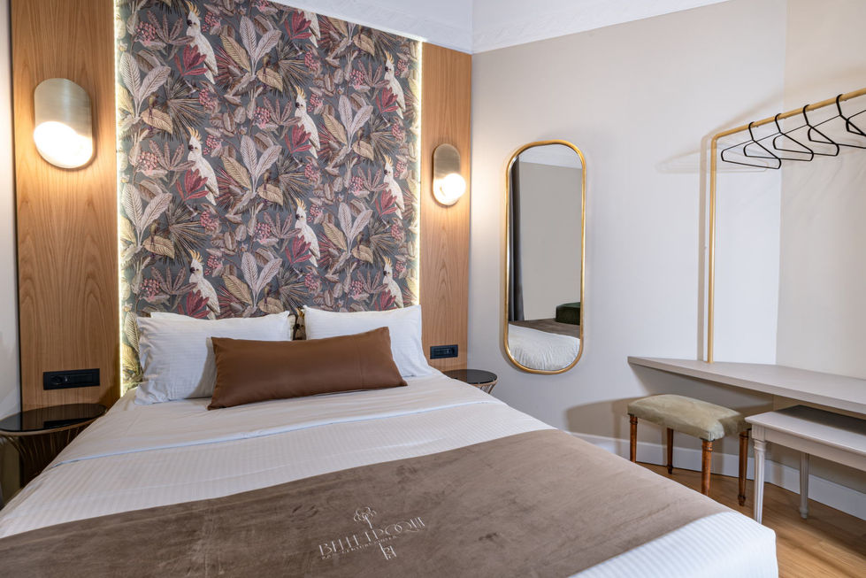Hotel bedroom with tropical-patterned headboard, integrated LED backlighting and warm wall sconces.