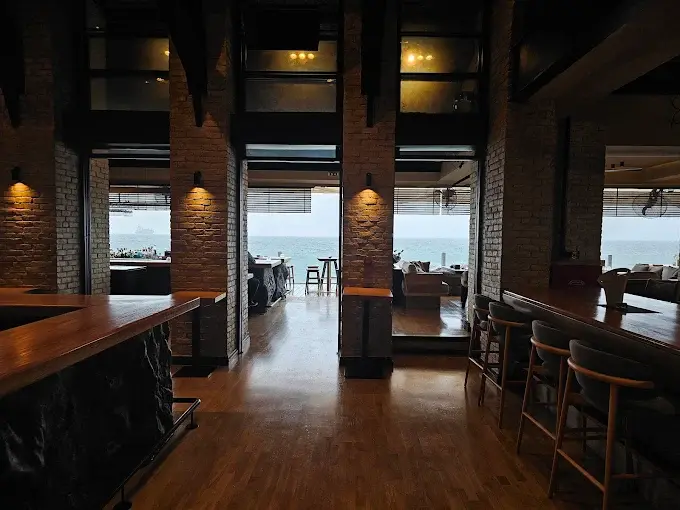 Restaurant hallway with wall sconces and natural light leading to sea view.