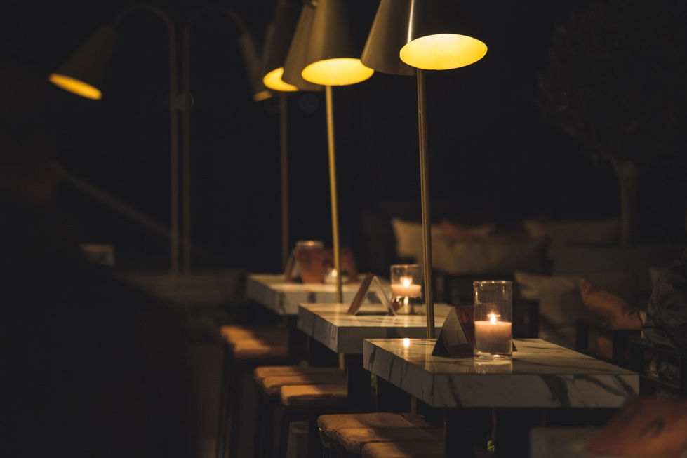 Candlelit marble tables with brass lamps at Ciel seaside restaurant creating intimate evening atmosphere.