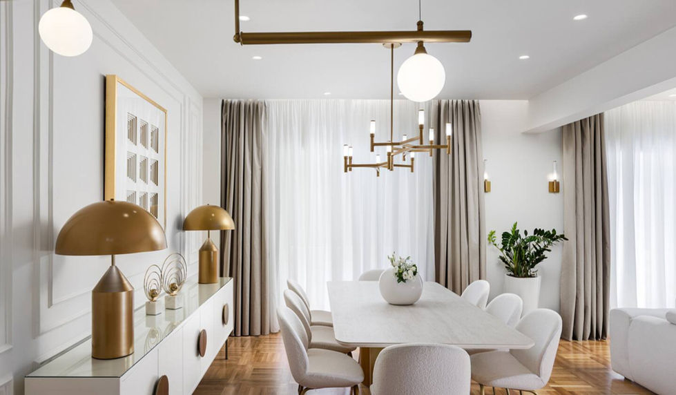 Dining room with golden table lamps, contemporary chandelier, and natural light filtering through sheer curtains.