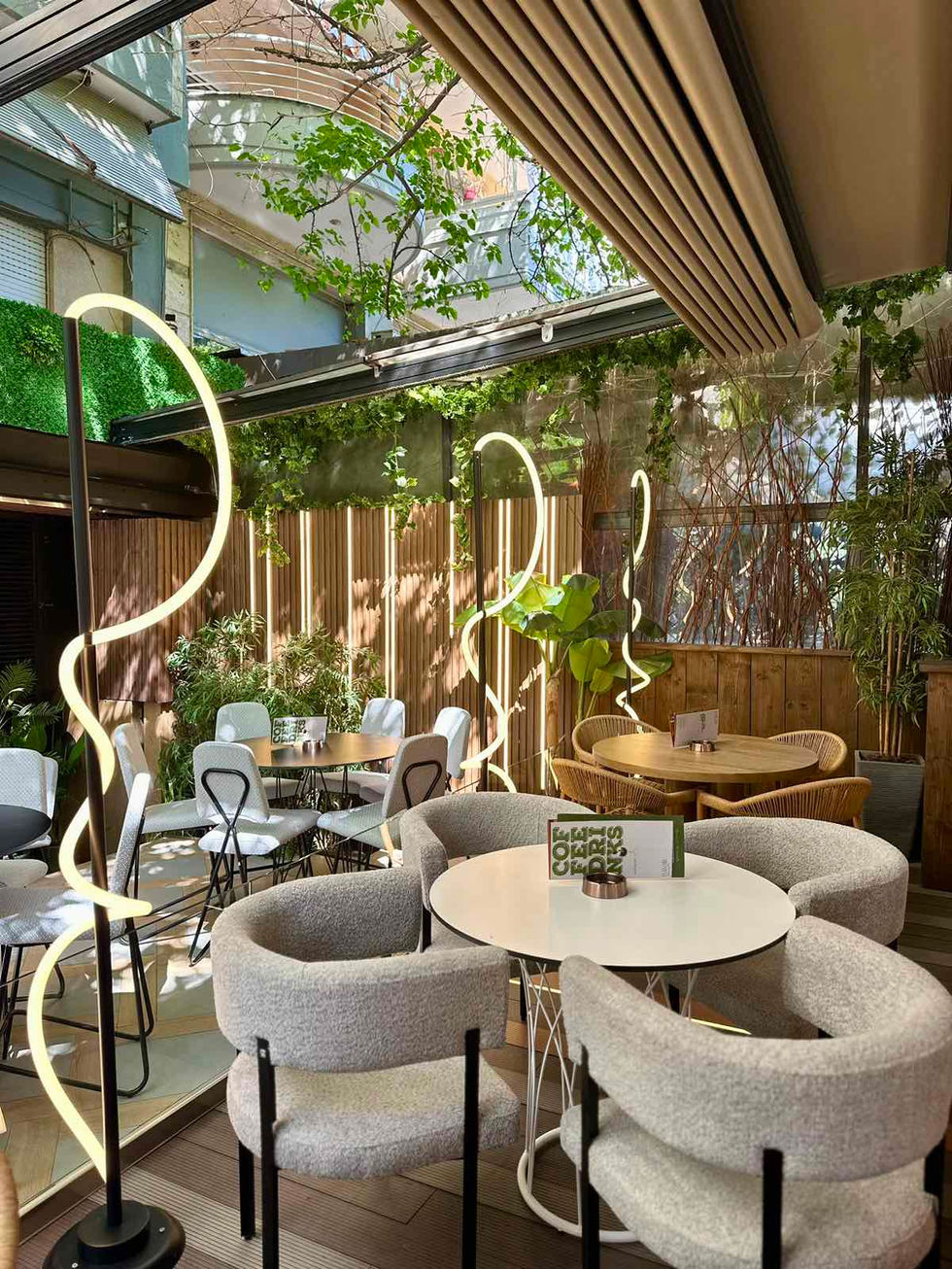 Dining space with greenery, upholstered chairs, and decorative sculptural neon flex floor lamps creating a modern atmosphere.