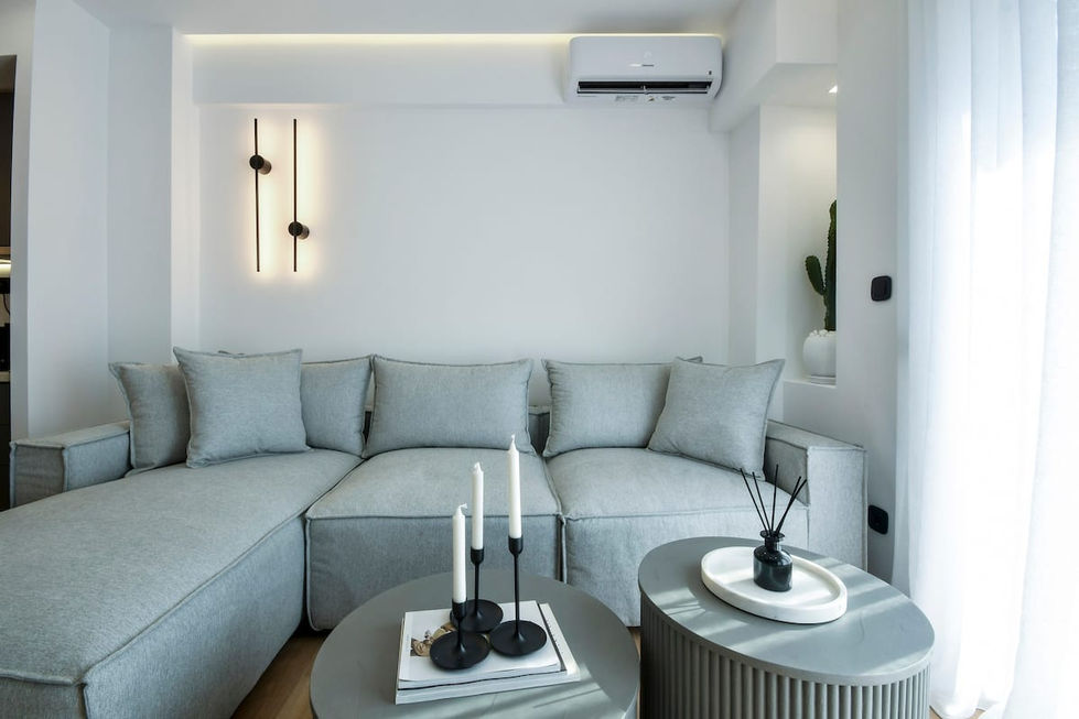Grey sofa with wall-mounted sconces – Minimal black wall sconces emit soft vertical glows, complemented by hidden ceiling cove lighting for ambient balance.
