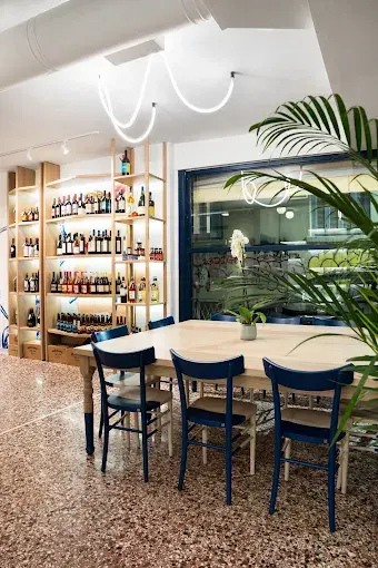 Interior view with wooden shelves and bottles, illuminated by curved ceiling light installation.
