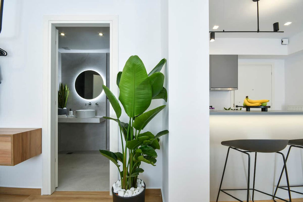 Hallway view towards bathroom featuring a circular LED backlit mirror as a striking focal point, paired with subtle ceiling downlights.