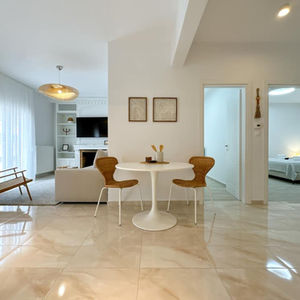 Open-plan living and dining area with wall spotlights and pendant lighting enhancing modern neutral design.