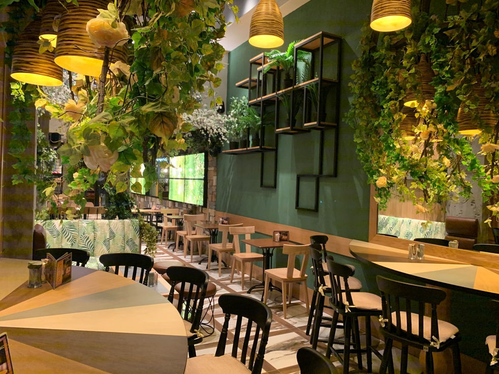 Biophilic restaurant interior with layered pendant lighting, hanging greenery, and cozy ambient glow.
