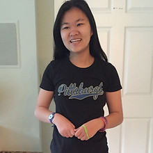Young woman smiling, wearing a black "Pittsburgh" t-shirt.