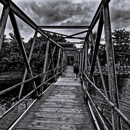 Old pedestrian footbridge crossing to the roadless end of the Teahupo'o peninsula, black and white, Tahiti