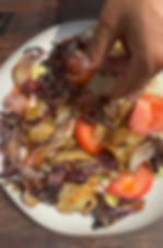 adding kalamata olives to the plate of Greek salad and grilled calamari