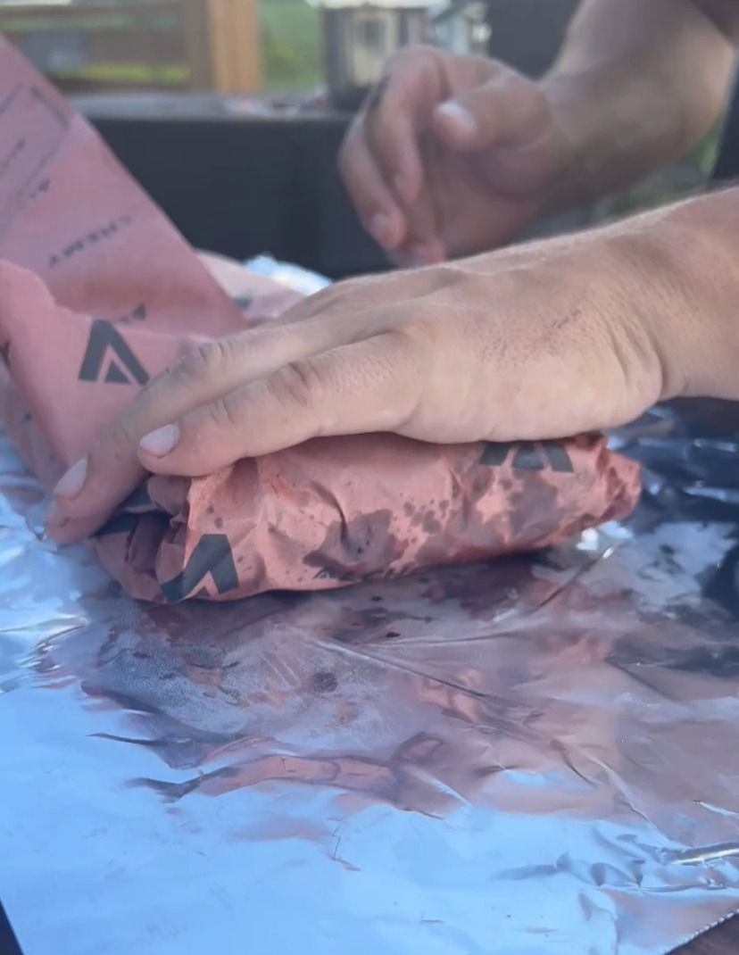 the smoked ribs with gochujang bbq sauce being wrapped in parchment paper then tin foil