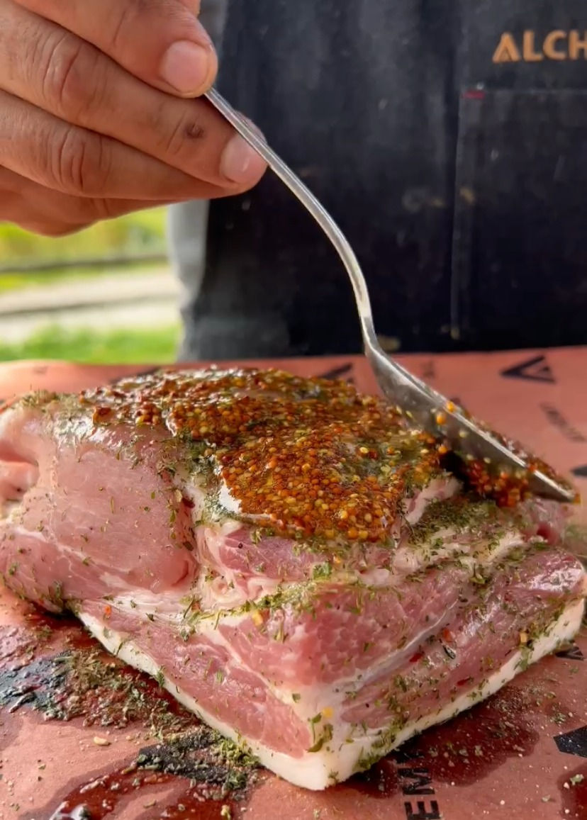 pork loin being covered with grainy dijon mustard and honey mixture