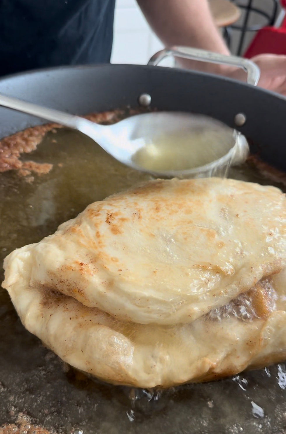 the panzerotto in hot oil being fried and the oil being poured over top with a spoon