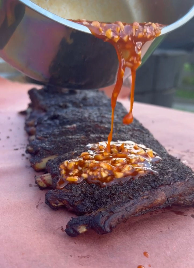 goghujang bbq sauce being poured onto smoked ribs