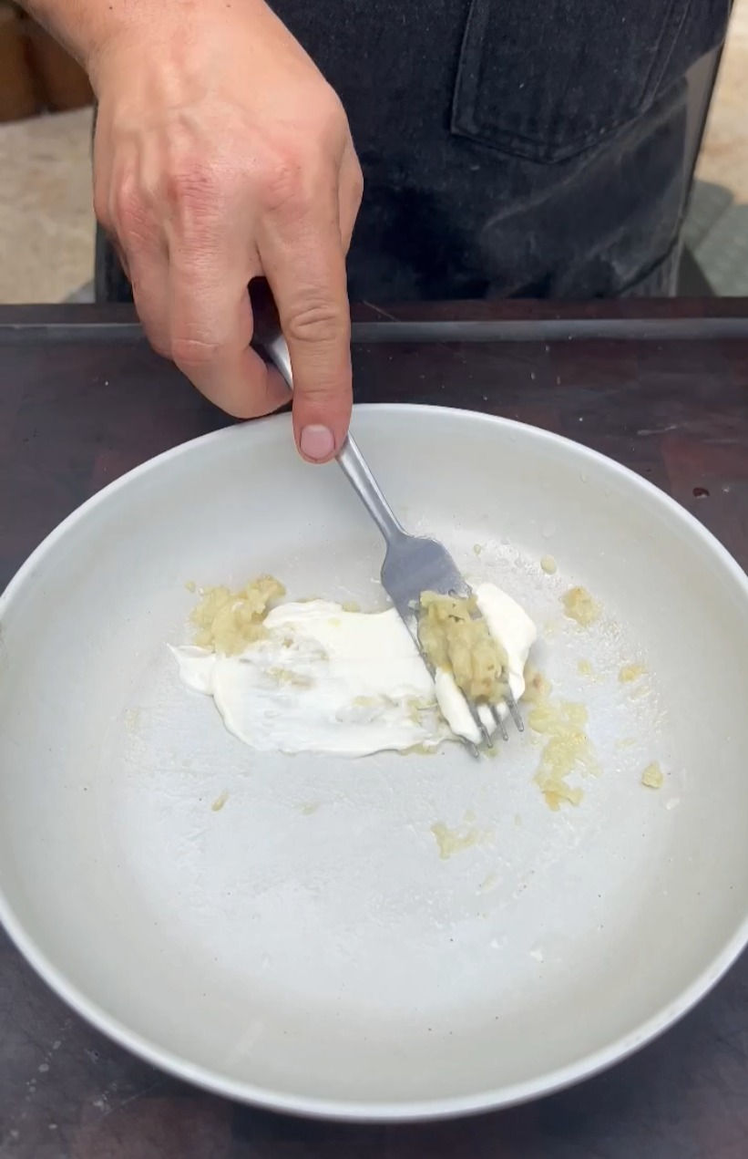 the fried garlic being mashed with a fork with lemon juice and mayo