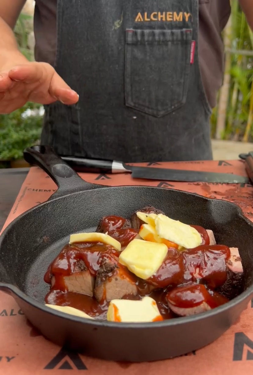 smoked brisket burnt ends in a cast iron pan with bbq sauce and butter