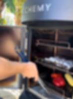 adding the shrimp skewers, peppers and corn to the Alchemy smoker