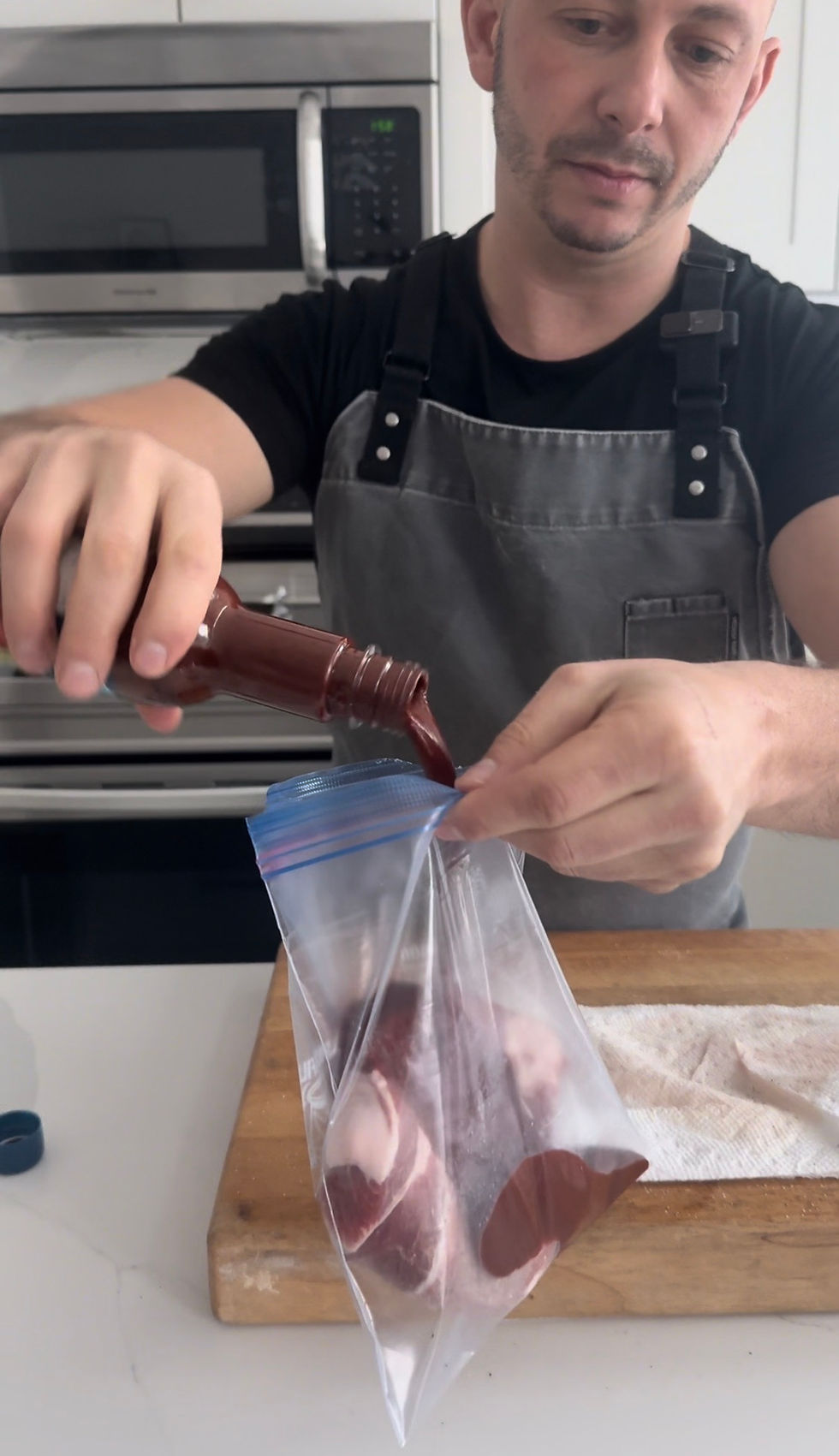 chef Matt Basile pouring al pastor marinade into a bag with the pork shoulder steak