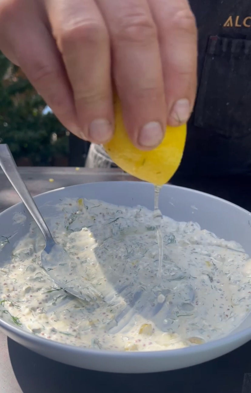 fresh lemon juice being squeezed into the bowl of tartar sauce