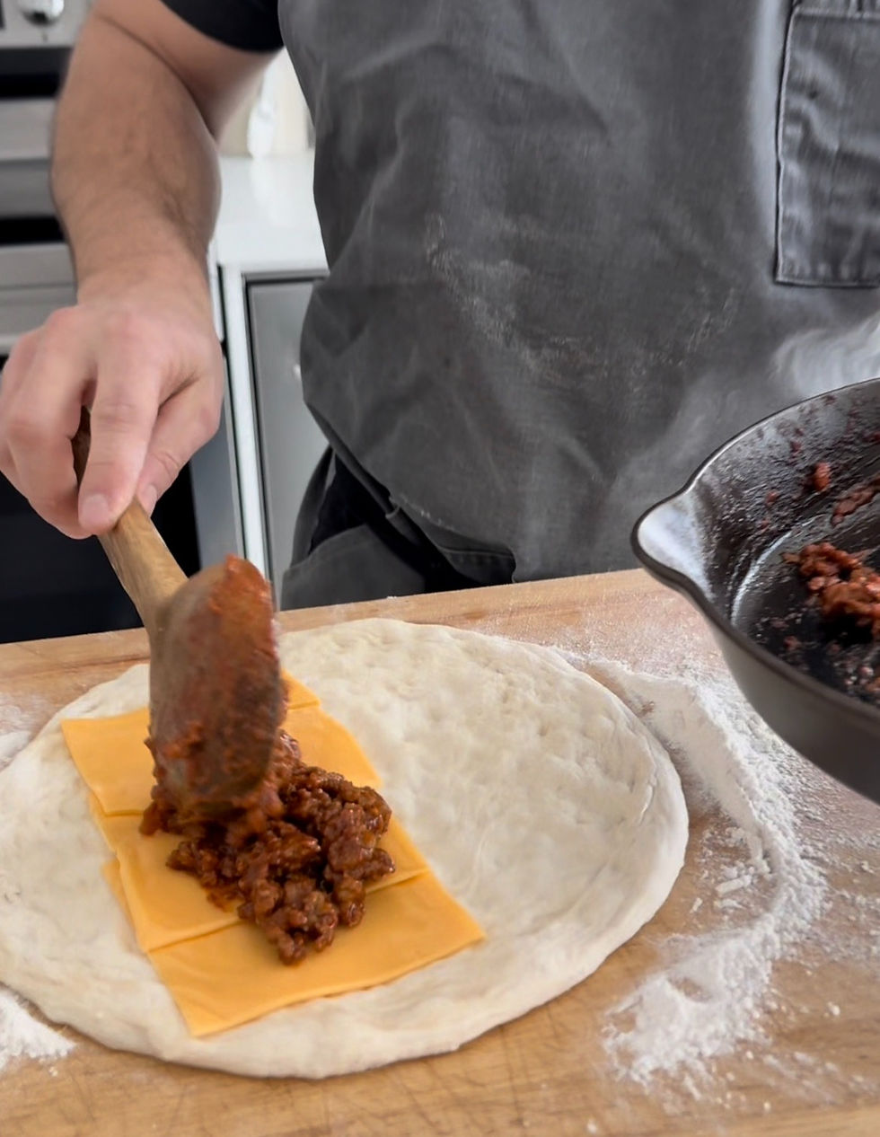 adding the cooked chorizo to the rolled out pizza dough with American cheese