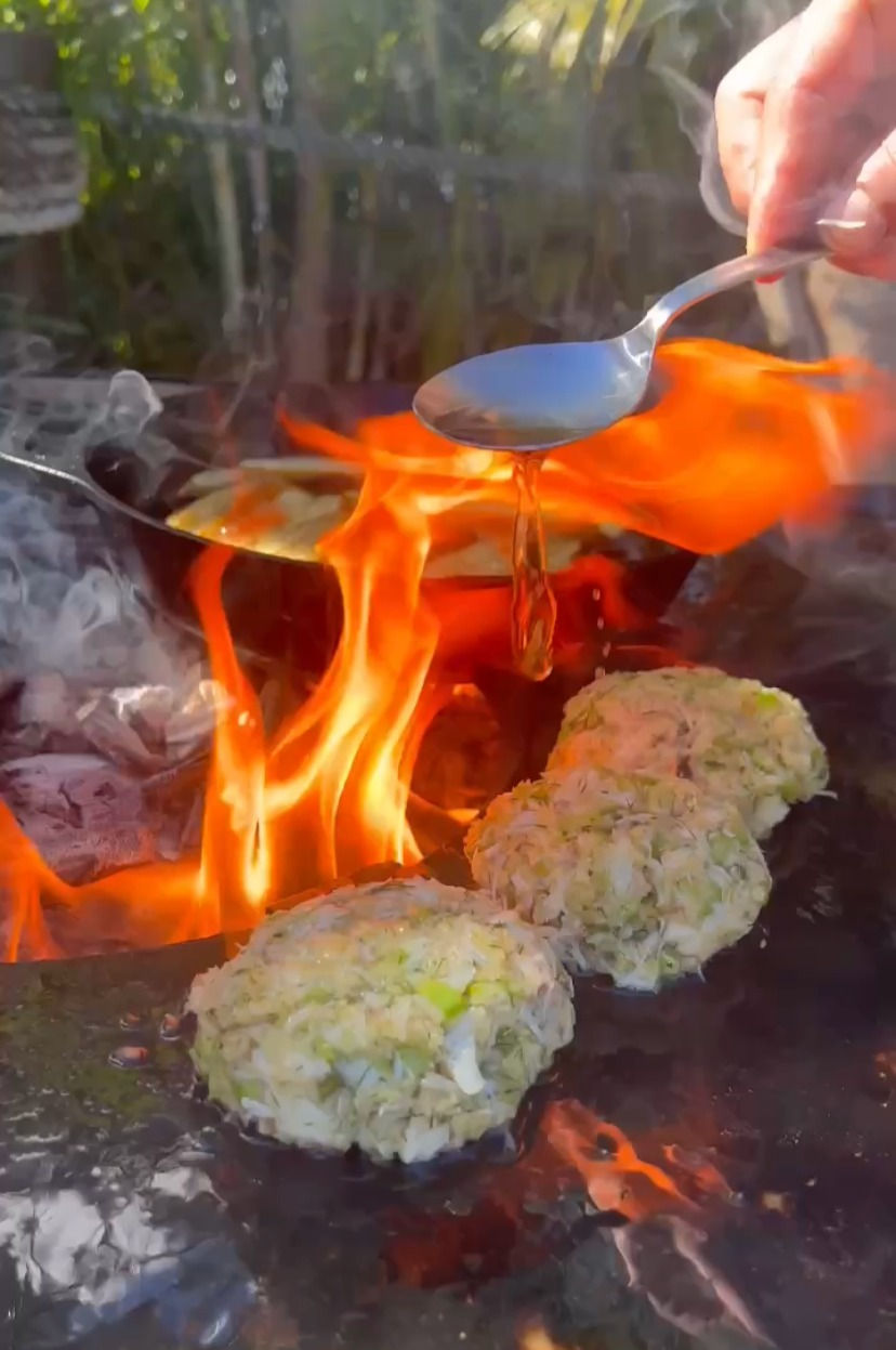 crab cakes on the plancha with oil being drizzled over them