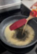 chicken broth concentrate being slowly poured into a pan with melted butter and flour