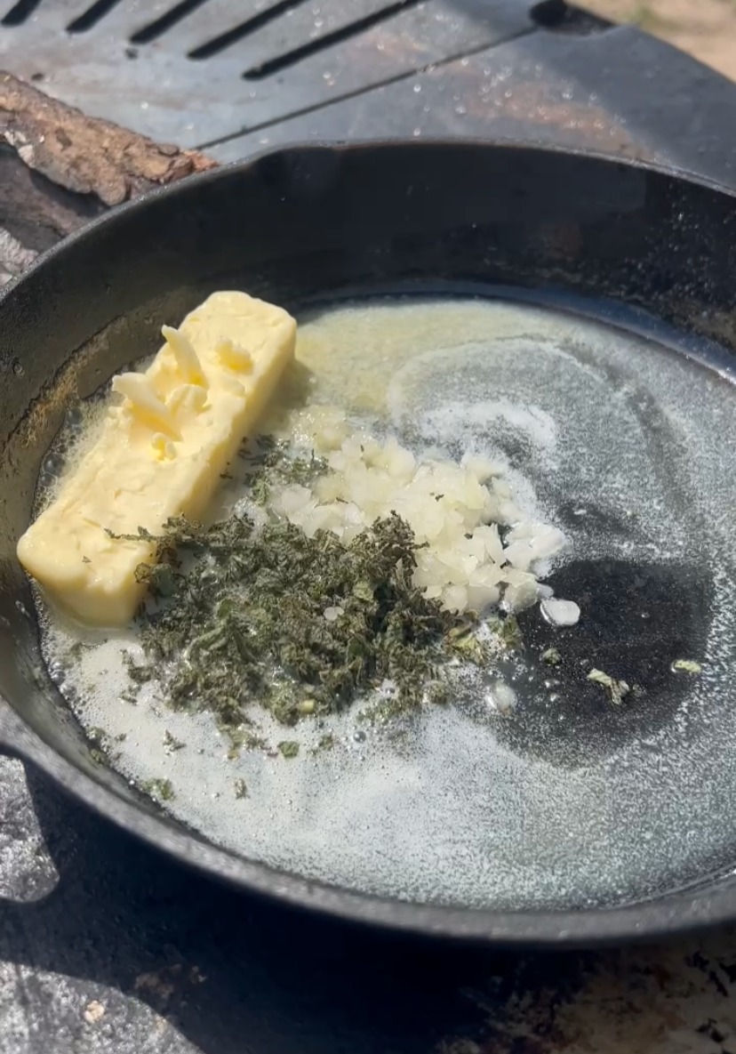 chopped onions, sage and butter in a cast iron pan on the plancha