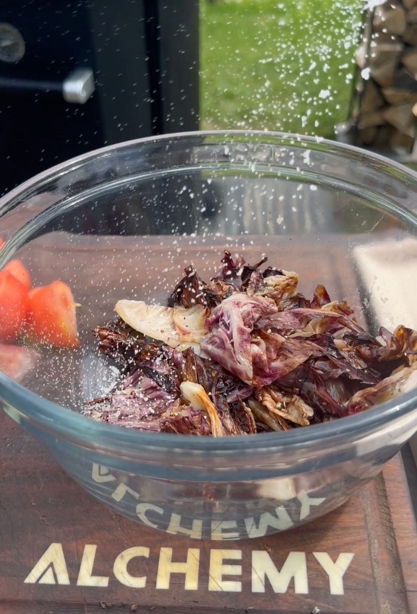 grilled radicchio being salted in a bowl