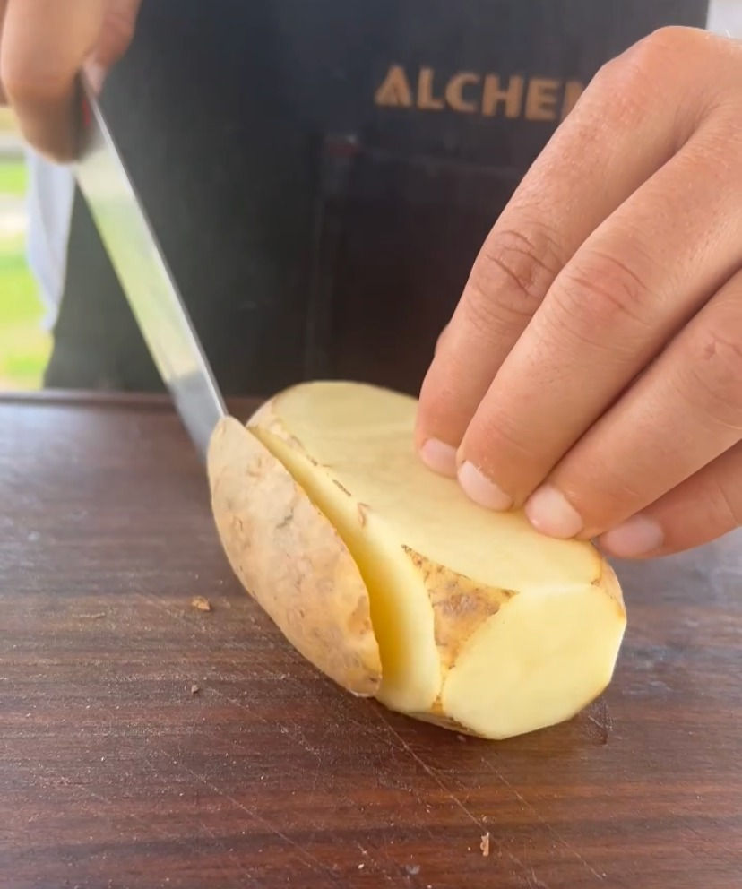 cutting the skin of a potato to turn it into a brick shape
