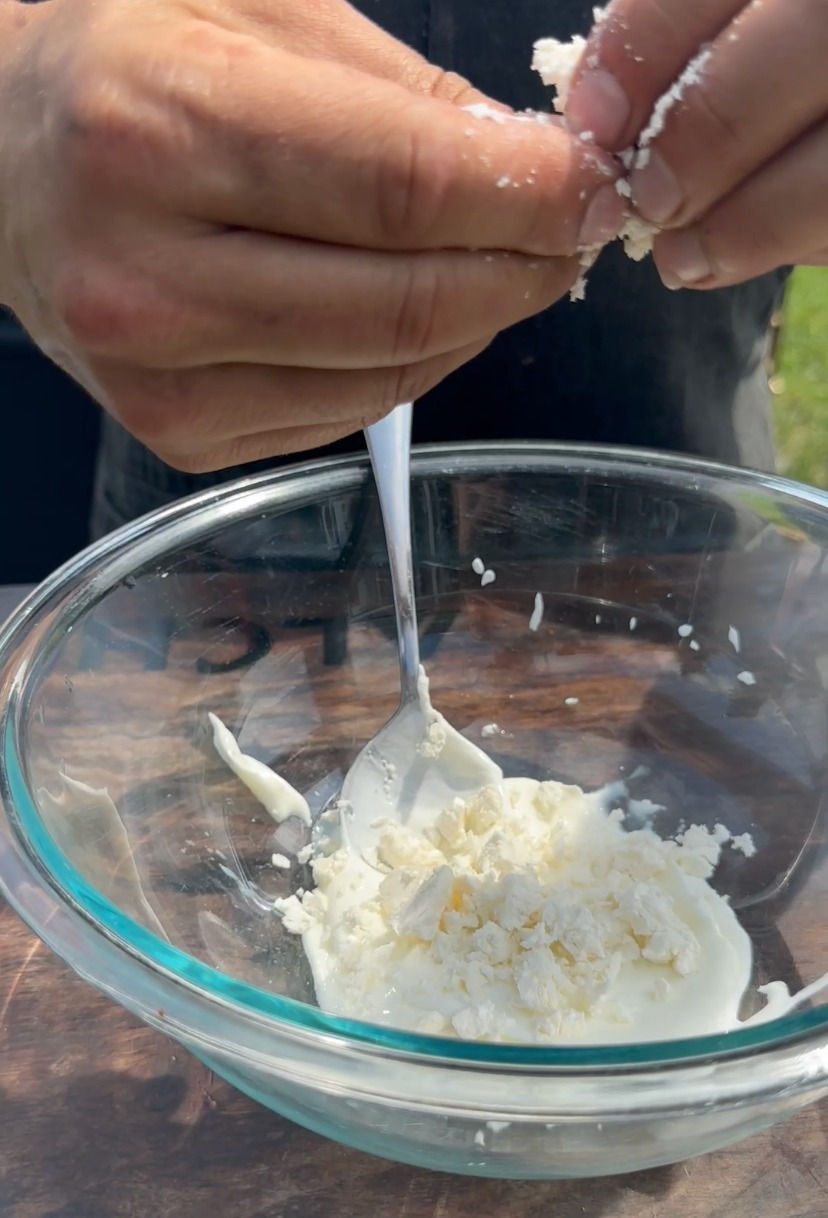 feta being crumbled into a bowl with Greek yogurt