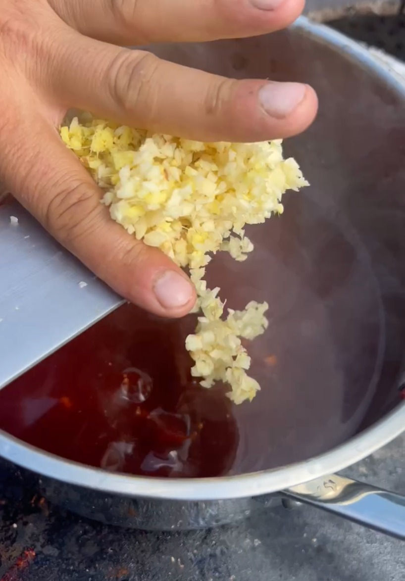 chopped ginger and garlic being added to the goghujang bbq sauce pot