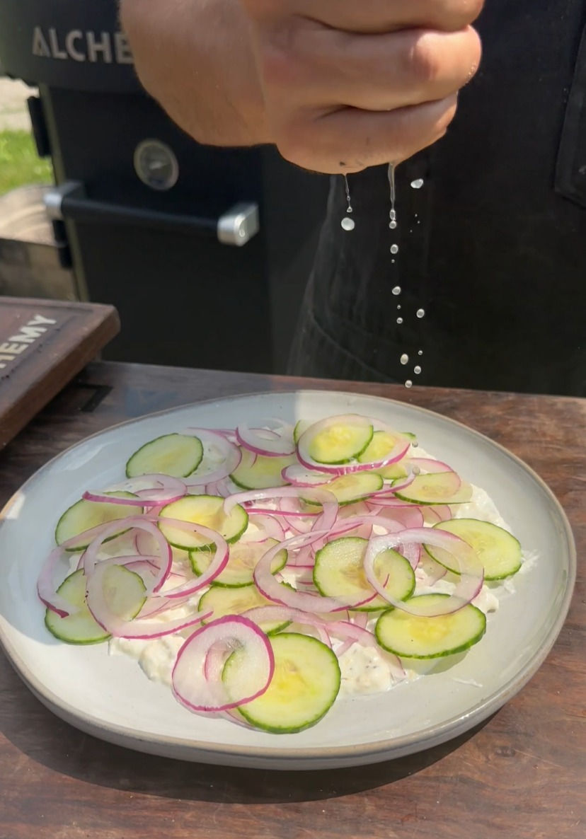 squeezing fresh lemon juice over a plate with the whipped feta and sliced cucumber and red onion