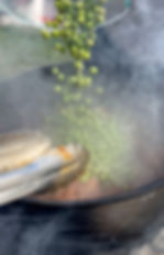 fresh peas being poured into the pot of braising smoked lamb