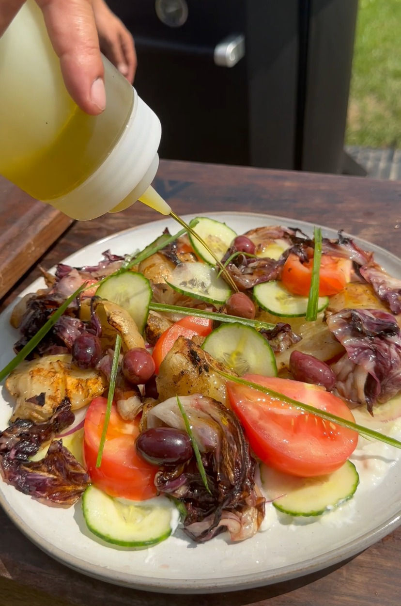 drizzling olive oil over the grilled calamari Greek salad