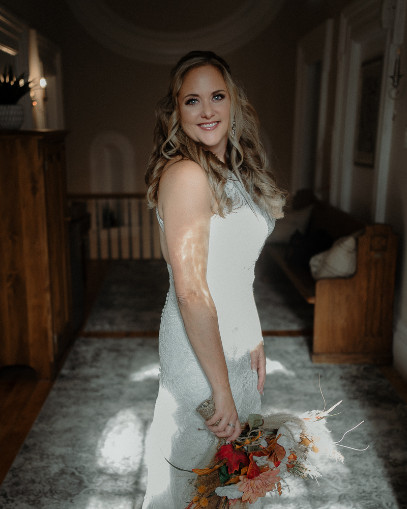 Mariée qui souri à la caméra, bouquet à la main