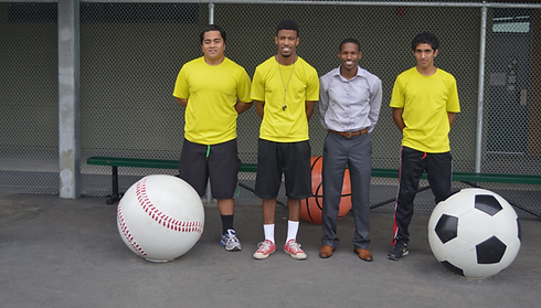 CF Fitness Staff members in yellow and grey shirts next to a giant softball and soccor ball