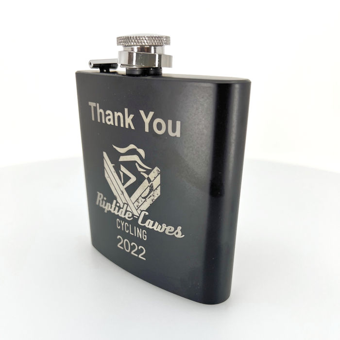 A black hip flask with a silver lid is engraved with the words "Thank You" and the logo