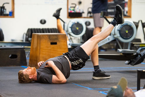 Man doing single leg glute bridge in CrossFit class warmup