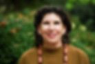 Ariel Weiss, Alexander Technique instructor, with curly dark hair smiles warmly at the camera