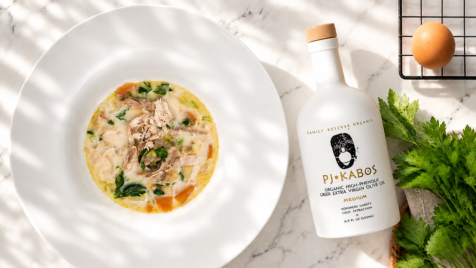 A bowl of Avgolemono Chicken Soup with a bottle of PJ Kabos High-Phenolic Olive Oil sitting ready to eat on a table.