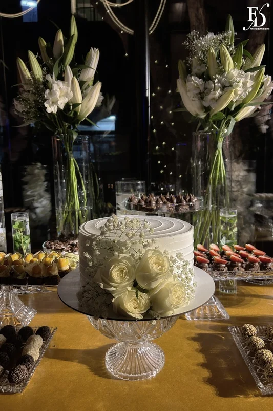 Bolo de casamento naked cake com rosas brancas e mosquitinho em cima de aparador dourado