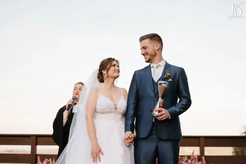 Noivos Nádia e Nikolas no altar ao ar livre com pôr do sol na Serra Gaúcha.
